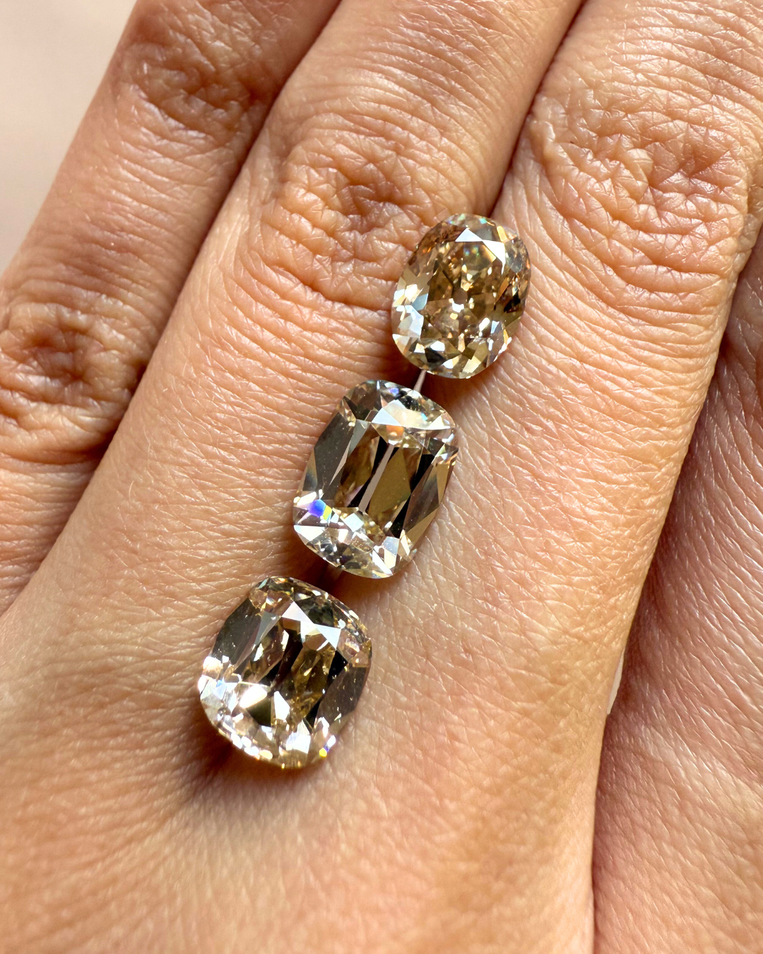 Three old mine cushion cut diamonds on a hand. 