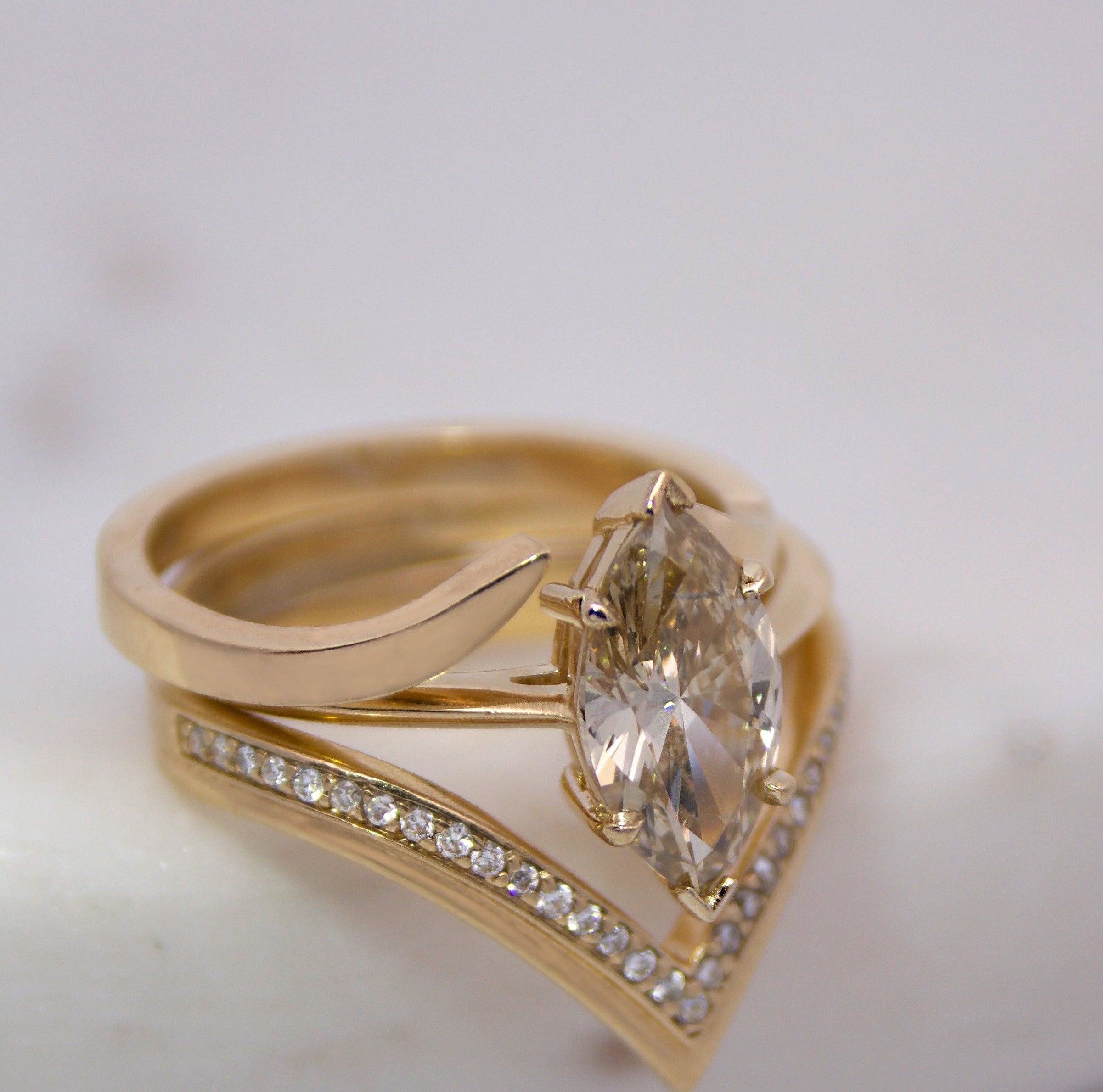 A ring stack featuring a champagne marquise cut diamond engagement ring and 14K yellow gold and diamond pave stacking bands.