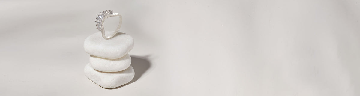 An angled baguette white diamond curve band in white gold set on top of three white stones on a grey background.