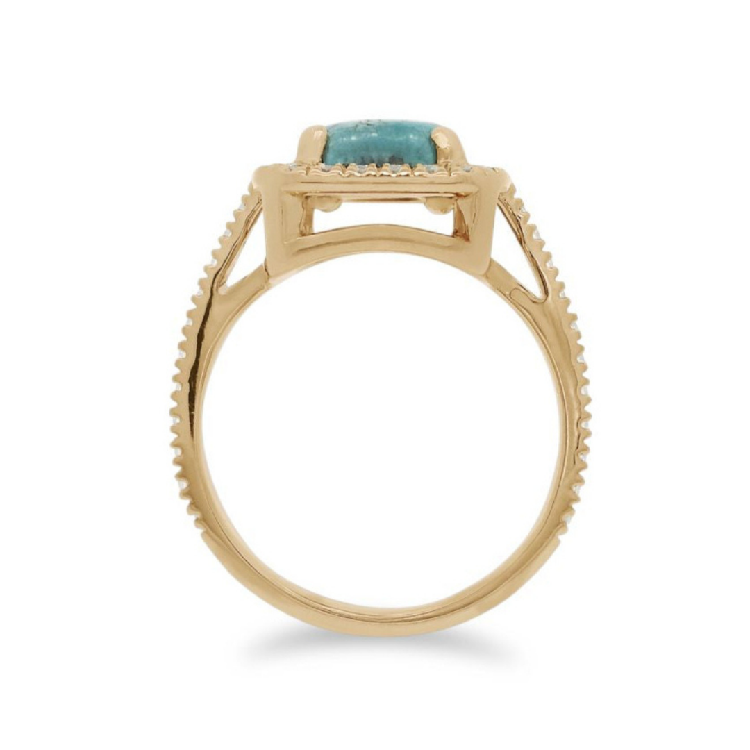 A side profile of a turquoise cabochon ring with a white diamond halo and pave on the band set in 14kt yellow gold.