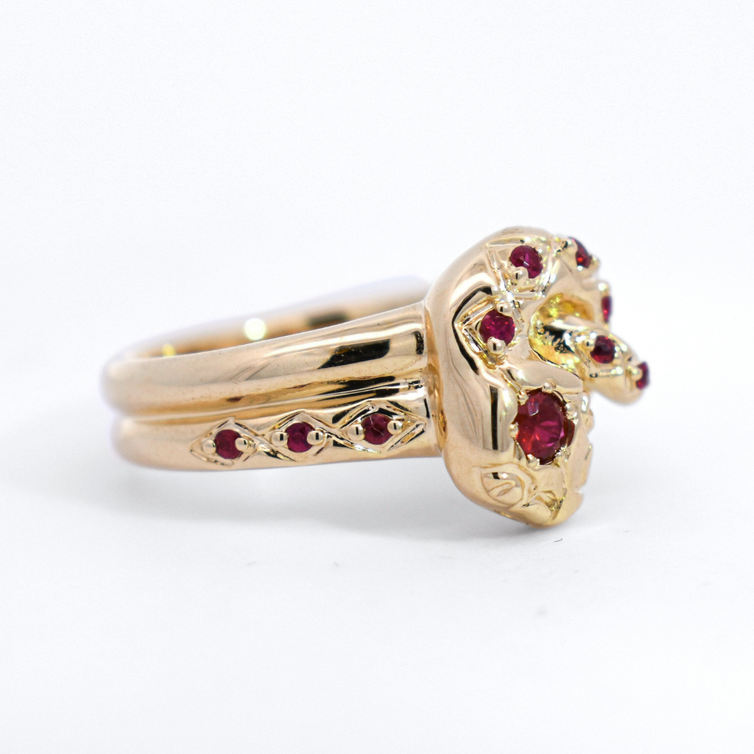 Side profile of a yellow gold ring in the shape of a serpent encrusted with rubies. 