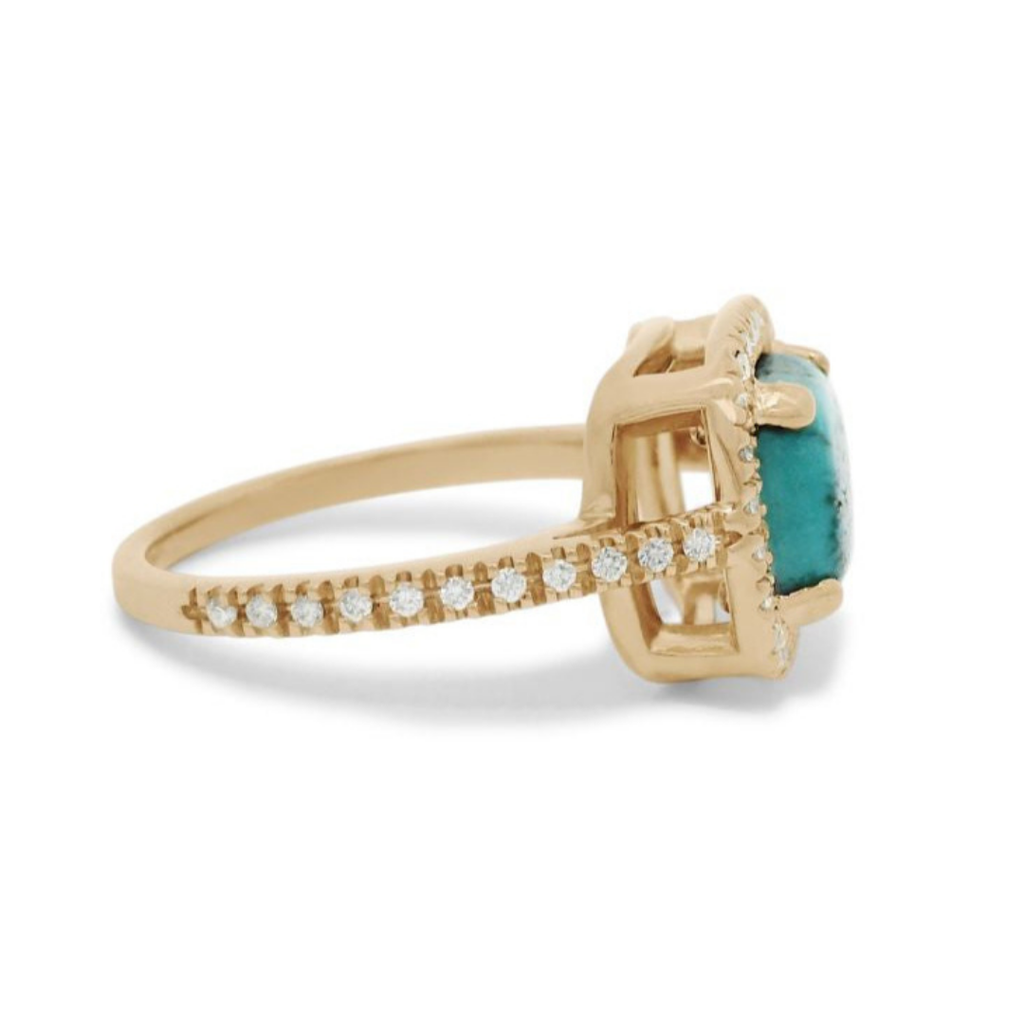 A side profile of a turquoise cabochon ring with a white diamond halo and pave on the band set in 14kt yellow gold.