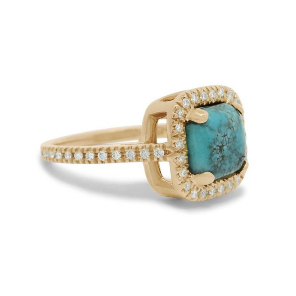 A 3/4 angle of a turquoise cabochon ring with a white diamond halo and pave on the band set in 14kt yellow gold.