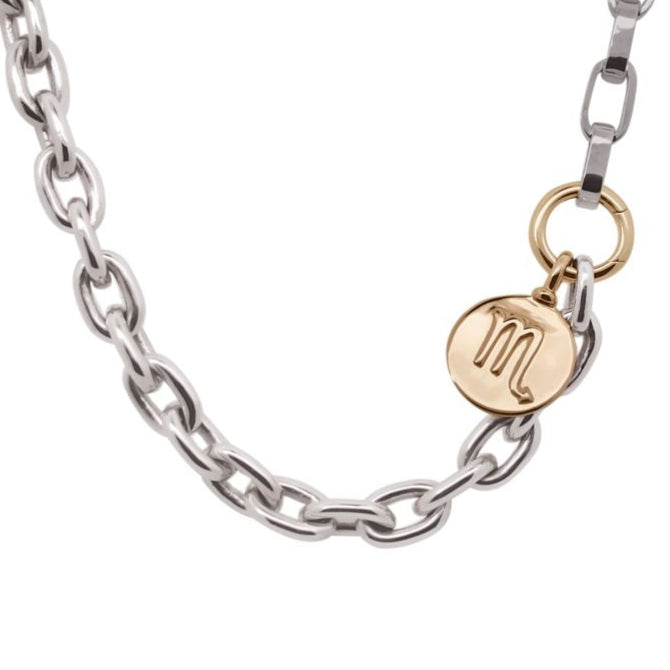 Silver chain necklace with a gold tag featuring a monogram on a white background