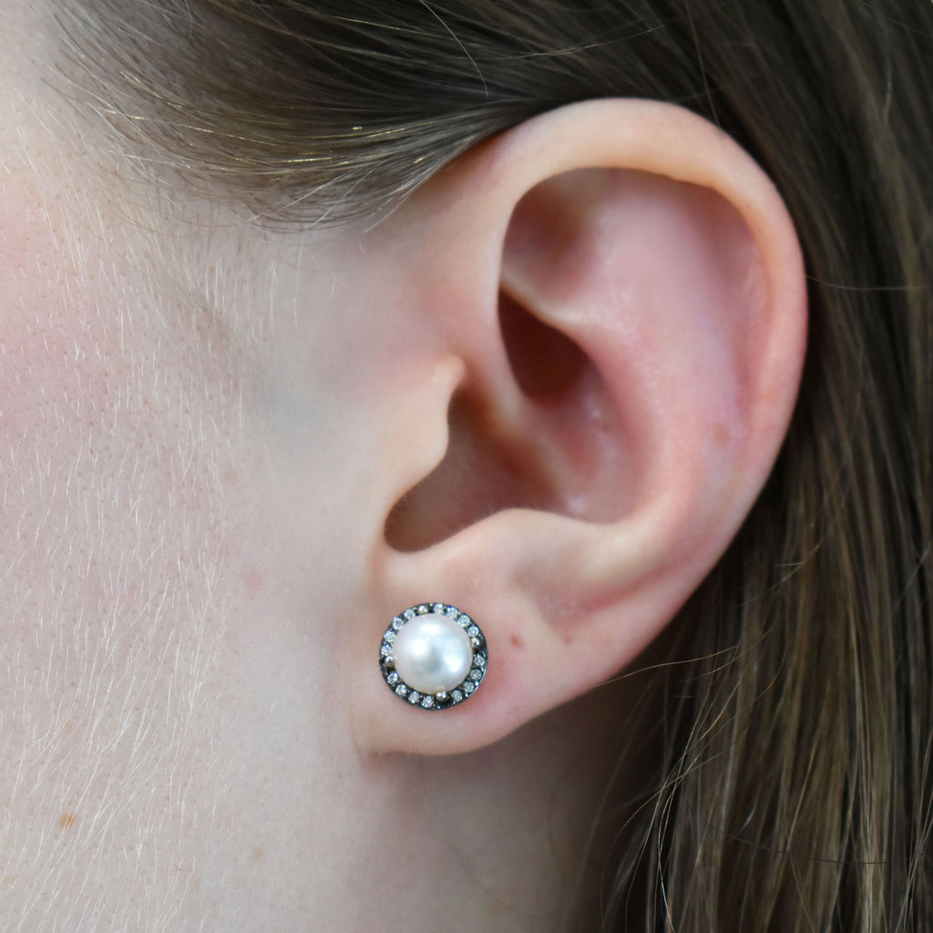 A medium pearl center stone earrings with a halo of white diamond set in yellow gold.
