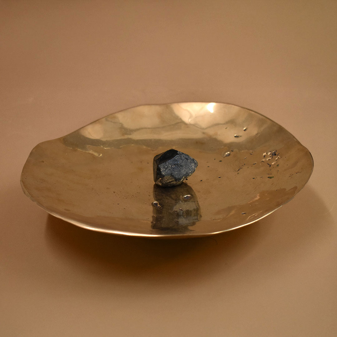 Bronze dish with a dark stone on a beige background