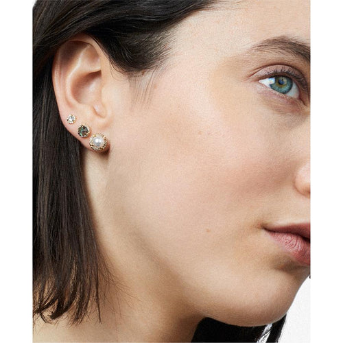 A light-complexion model with three halo studs on her ear, two medium sized and one tiny.