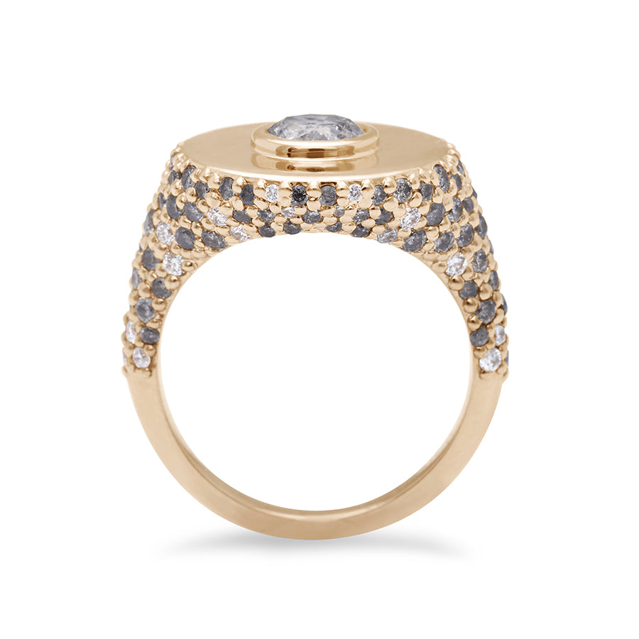 Side view of a round grey diamond bezel set in a signet style ring with white and grey diamond pave down the sides of the band set in yellow gold.