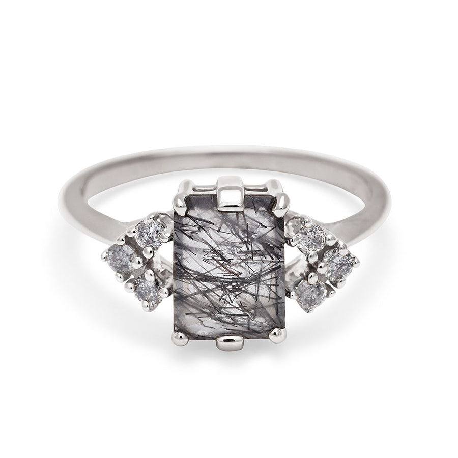 A ring with an emerald cut black rutilated quartz center with three round grey diamonds on either side in arrow shape, set in white gold., White Gold