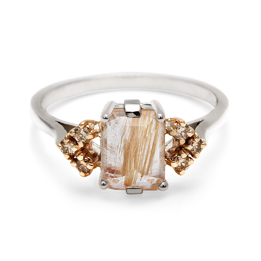 A ring with an emerald cut golden rutilated quartz center with three round champagne diamonds on either side in arrow shape, set in white gold., White Gold