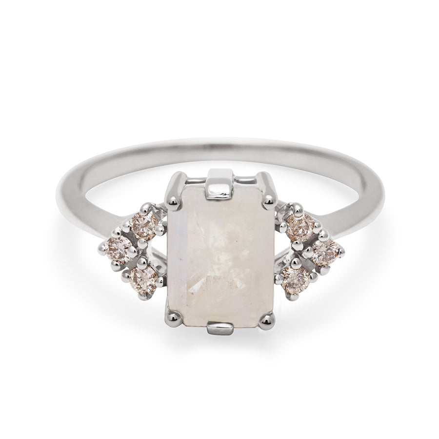 A ring with an emerald cut rainbow moonstone center with three round champagne diamonds on either side in arrow shape, set in white gold., White Gold