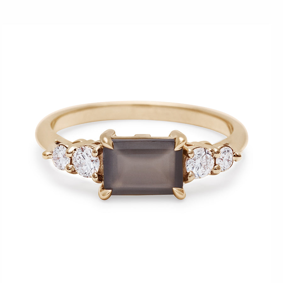 A ring with an emerald shaped grey moonstone center stone with two round white diamonds on either side set in yellow gold., Yellow Gold