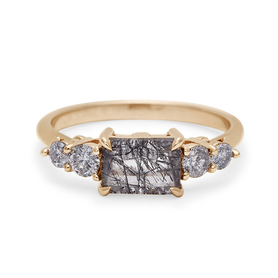 A ring with an emerald shaped black rutilated quartz center stone with two round grey diamonds on either side set in yellow gold., Yellow Gold