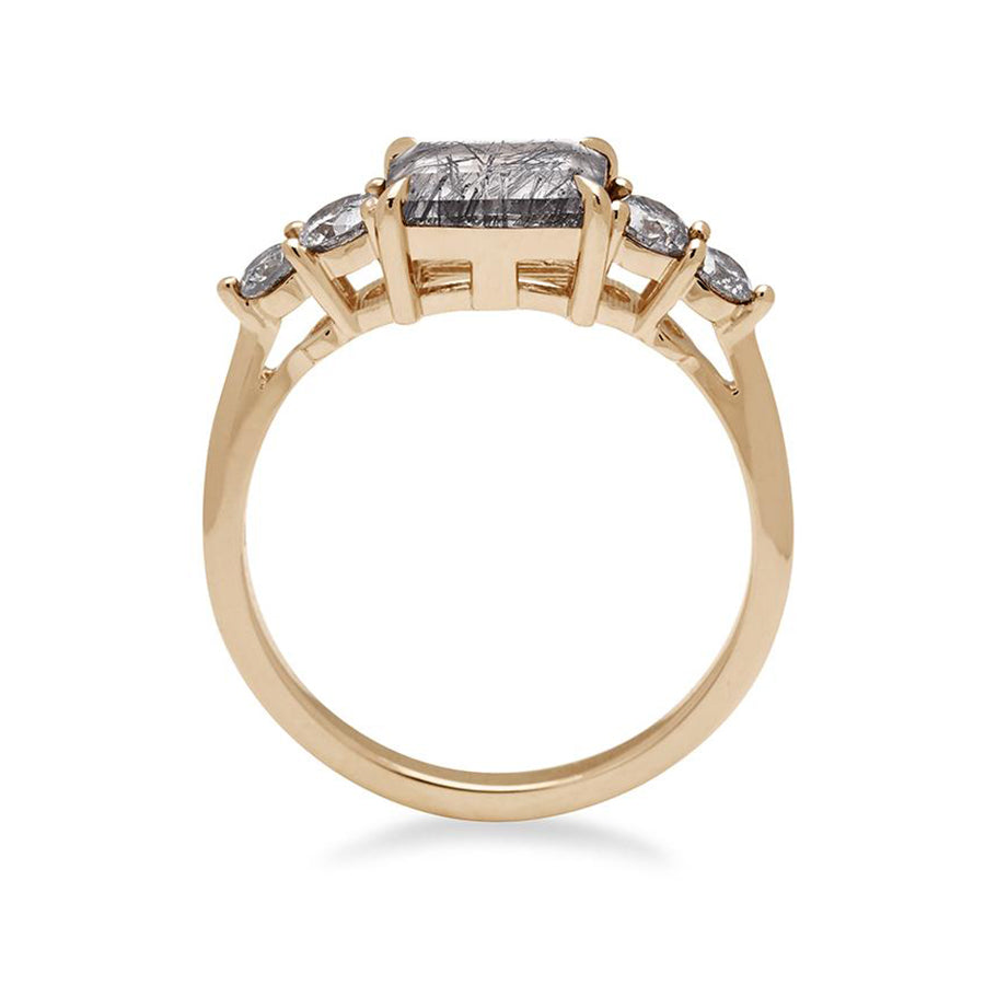 Side view of a ring with an emerald shaped black rutilated quartz center stone with two round grey diamonds on either side set in yellow gold., Yellow Gold