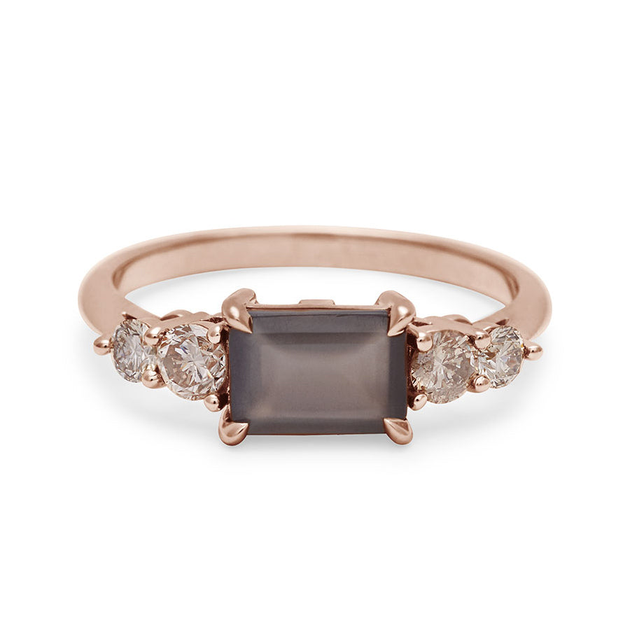 A ring with an emerald shaped grey moonstone center stone with two round champagne diamonds on either side set in rose gold., Rose Gold