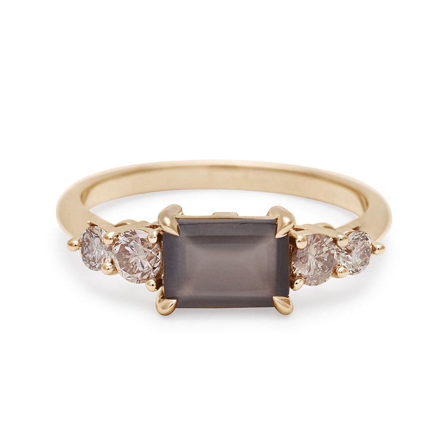 A ring with an emerald shaped grey moonstone center stone with two round champagne diamonds on either side set in yellow gold., Yellow Gold