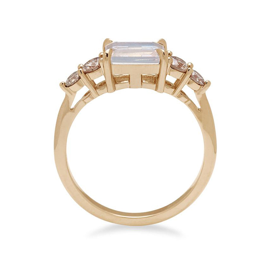 Side view of a ring with an emerald cut and shaped rainbow moonstone center stone with two round champagne diamonds on either side set in yellow gold., Yellow Gold