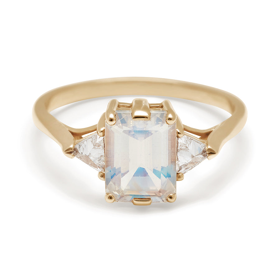 A three stone engagement ring with an emerald cut and emerald shape 11x7 rainbow moonstone center stone with white diamond trillion side stones set in yellow gold., Yellow Gold