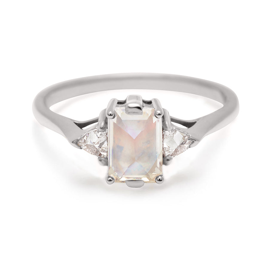 A three stone engagement ring with an emerald cut and emerald shape 7x5mm rainbow moonstone center stone with two white diamond trillion side stones set in white gold., White Gold