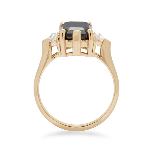 Side view of a three stone engagement ring with an emerald shape black diamond center stone with two white diamond trillion side stones set in yellow gold., Yellow Gold
