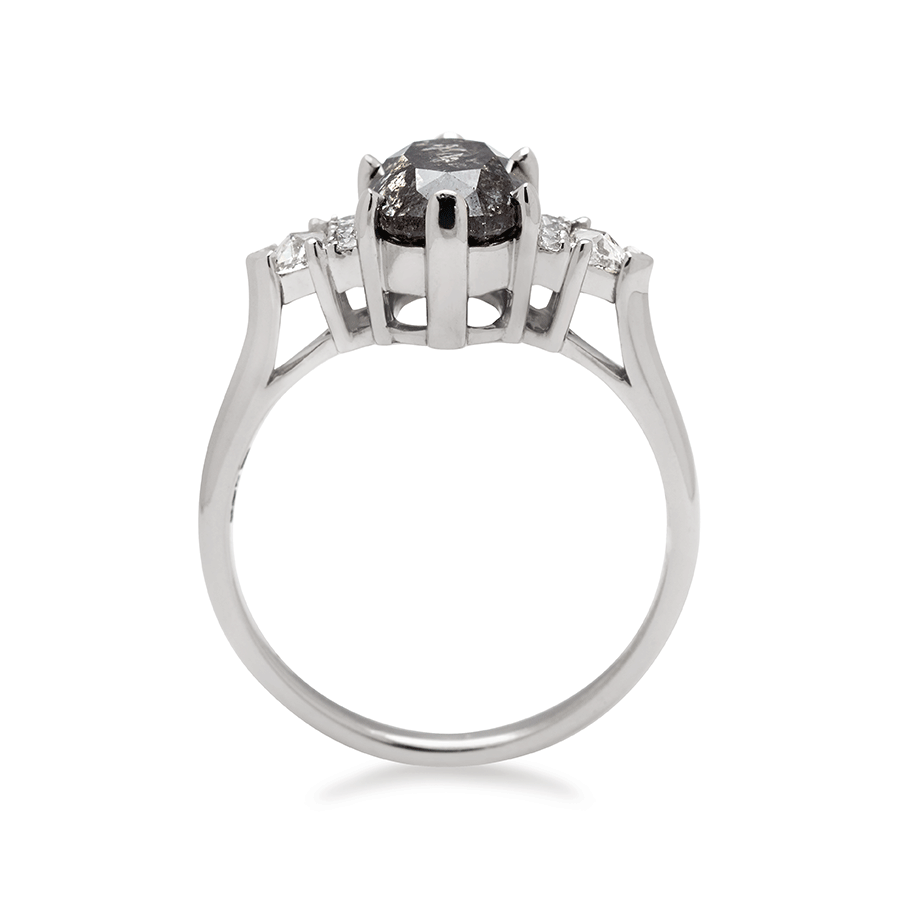 Side view of an oval shape 2.00ct painted black diamond center stone ring with three round white diamonds on either and two white diamond trillions on the outer edges of each side set in white gold.