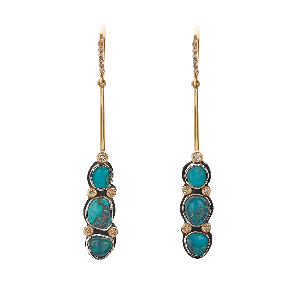 A pair of drop earrings with turquoise stones set in sterling silver and champagne diamond pave accent stones and on the earwire set in yellow gold.