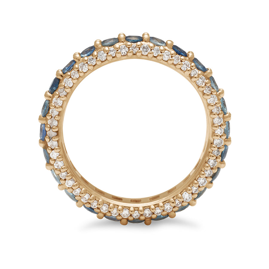 Side view of a band with round Montana sapphires set in eternity around a yellow gold band with white diamond pave accents on both top and bottom of the band.