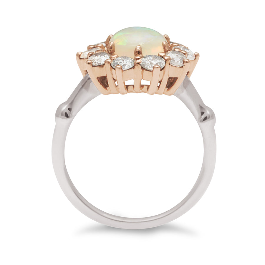 Side view of a ring with a round opal center stone surrounded by round grey diamonds set in a rose gold basket and a white gold band.
