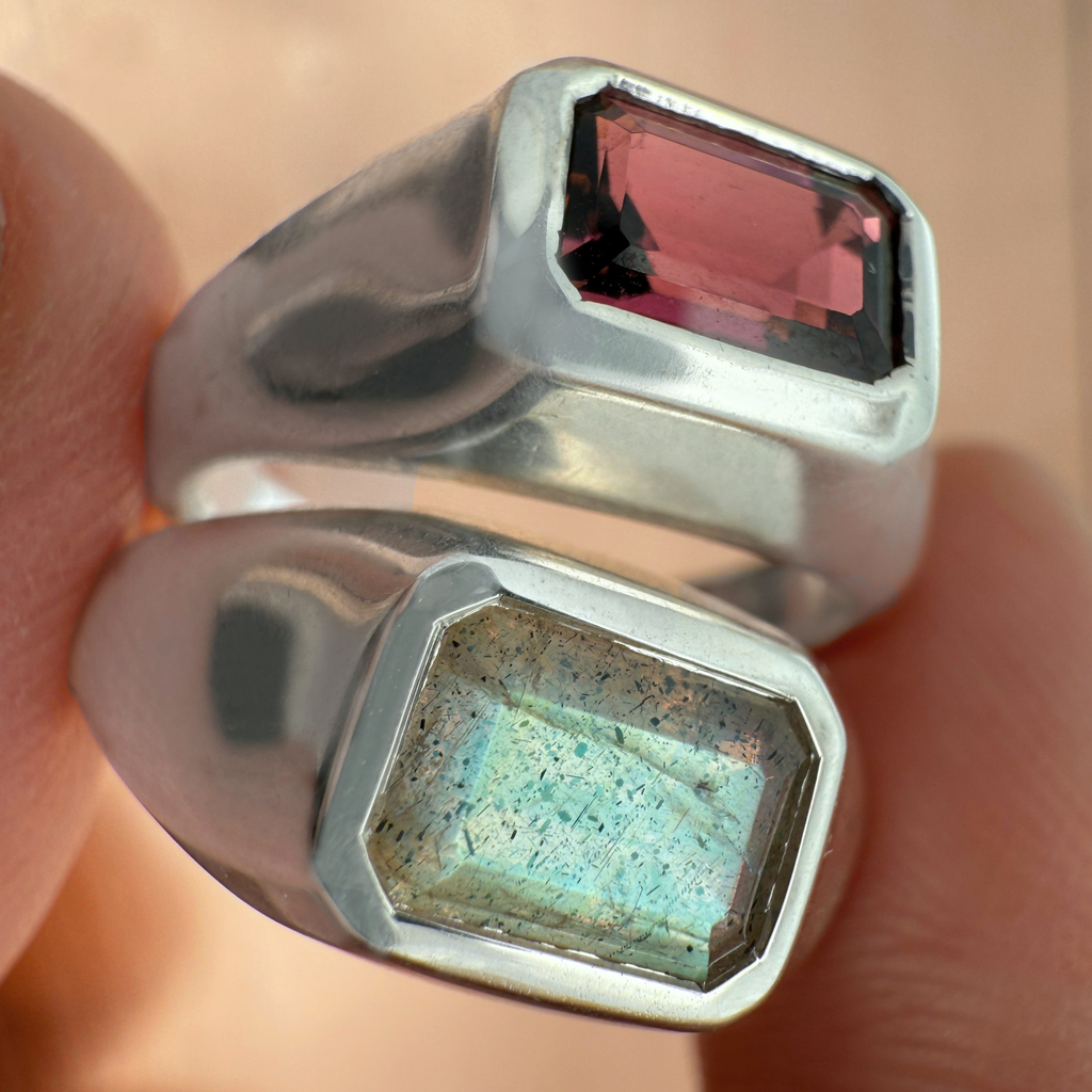 Two sterling silver gemstone rings between fingers
