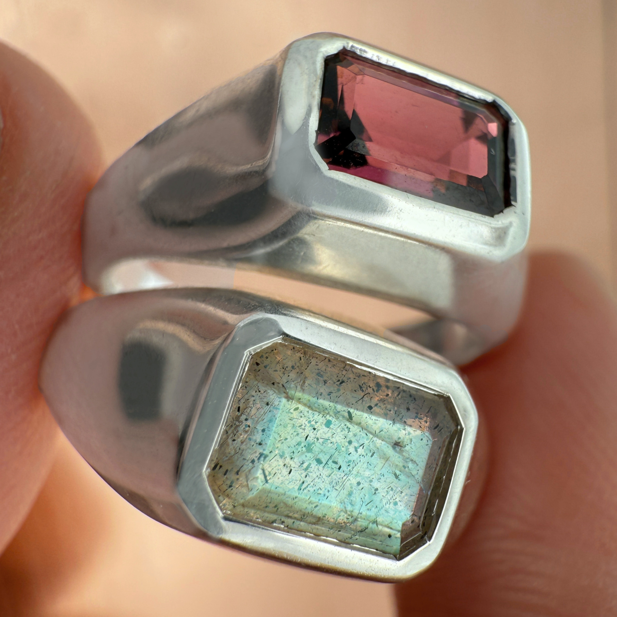 Two sterling silver gemstone rings between fingers