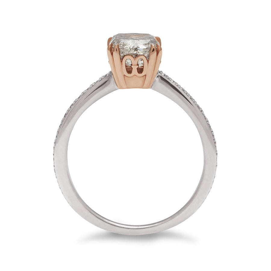 Side view of a solitaire ring with a cushion cut grey diamond set in a rose gold basket with white diamond pave on the white gold band.