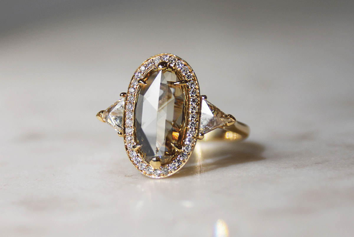 A custom engagement ring by Anna Sheffield featuring a large rose cut champagne diamond and a white diamond halo in 14k yellow gold. 