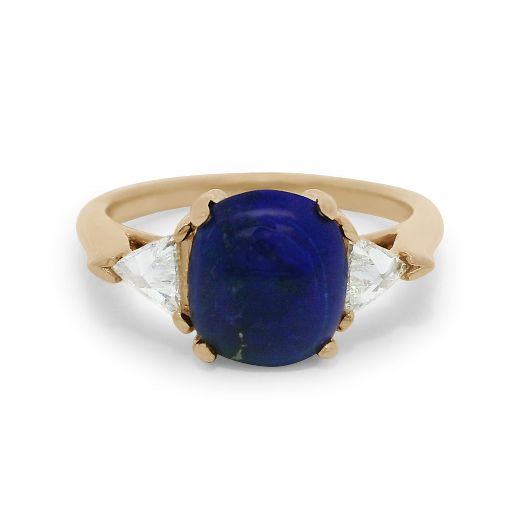A lapis cabochon ring with white diamond trillion side stones set in 14k yellow gold. 