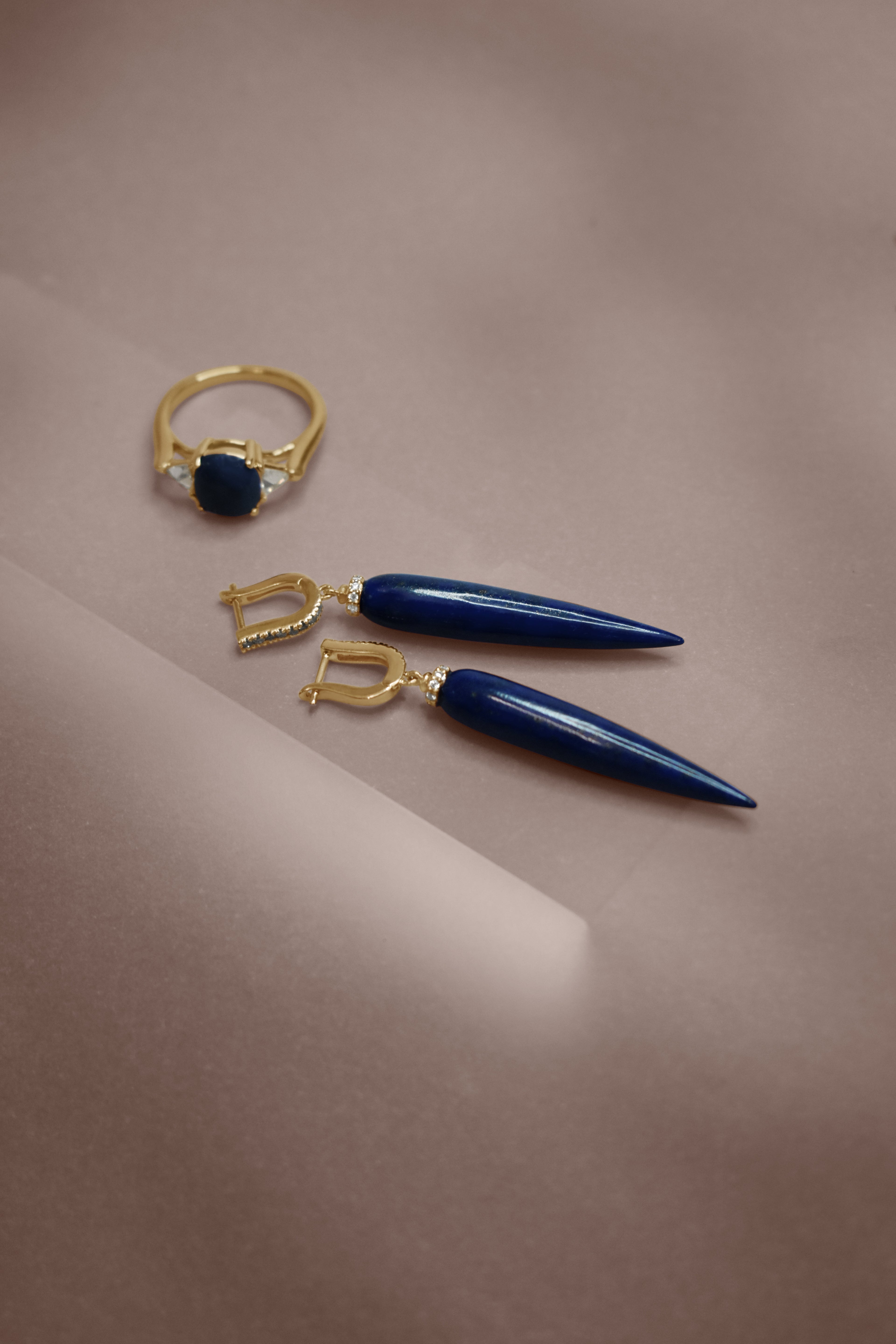 A pair of U hoop earrings with pointy drop lapis stones with a white diamond halo at the component that attaches the stone to the top set in yellow gold.
