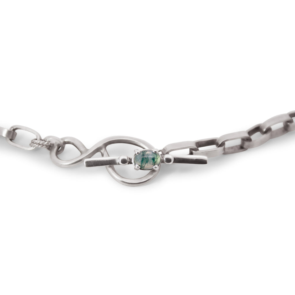 Silver chain necklace with a green moss agate gemstone on a white background