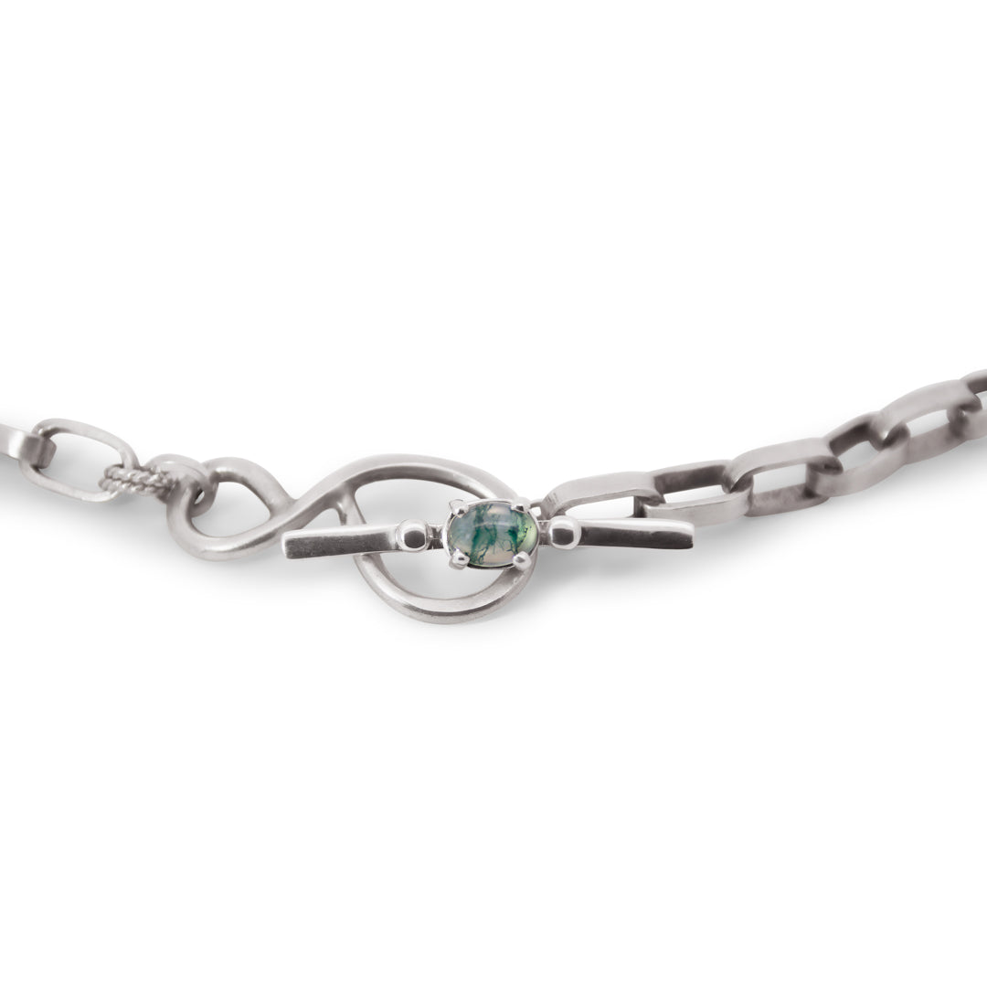 Silver chain necklace with a green moss agate gemstone on a white background