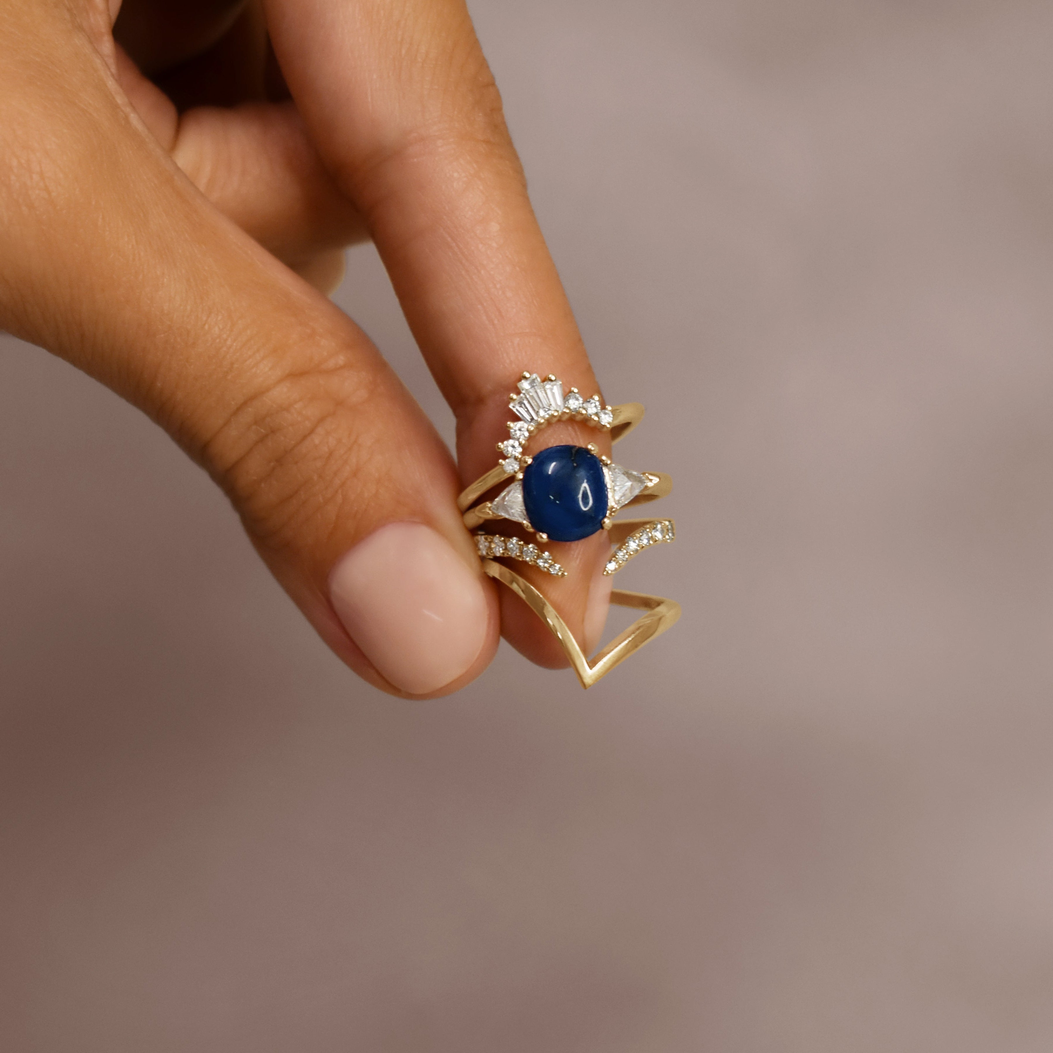 A lapis cabochon ring with white diamond trillion side stones set in 14k yellow gold. 
