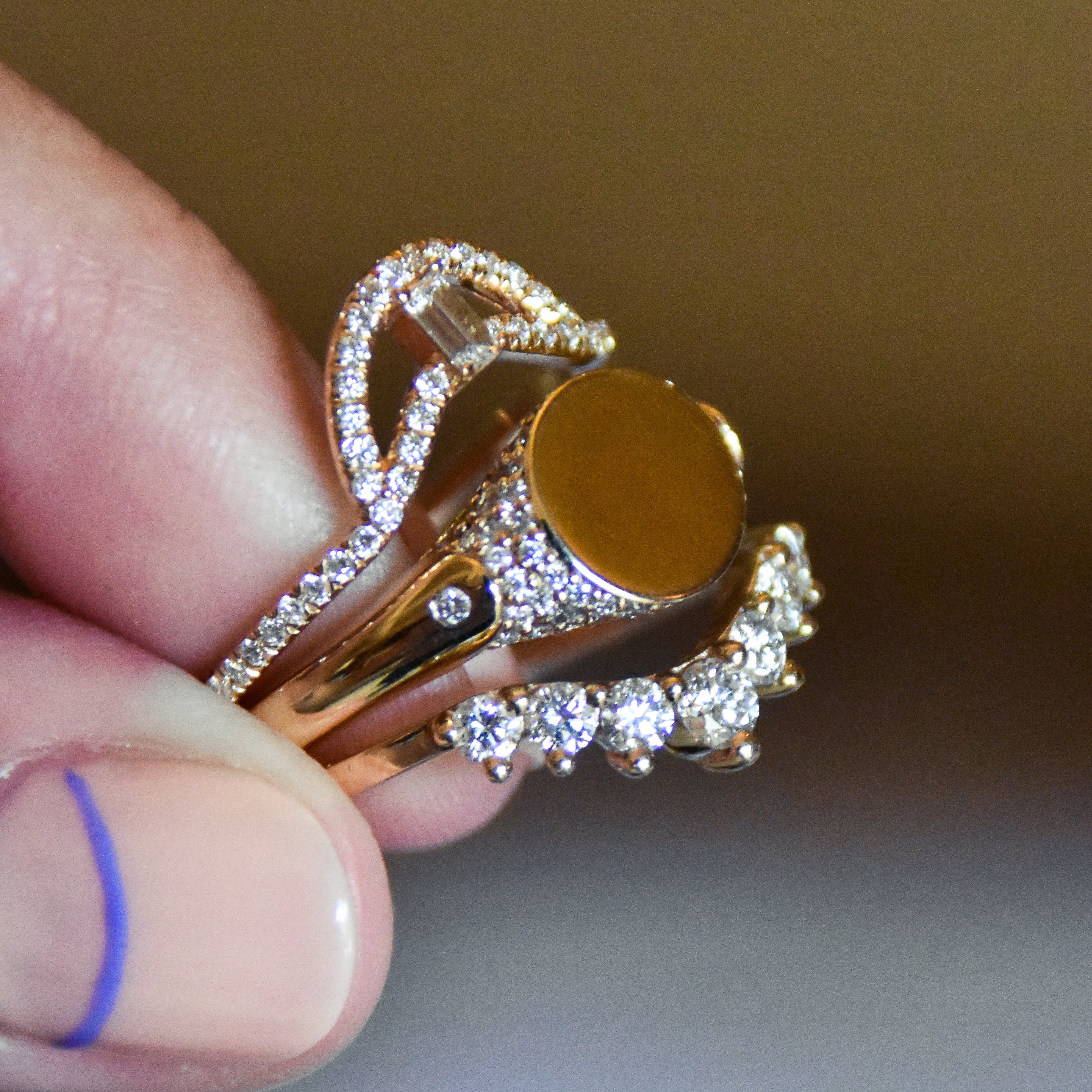 A solid gold signet ring with two white diamond accents on either side and a pave set around the top of the ring and set in yellow gold stacked between two diamond dusted curve bands.