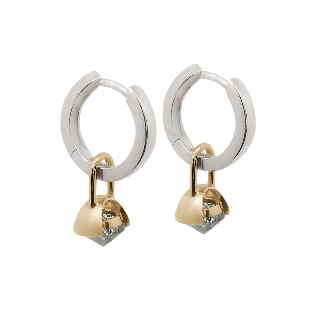 Pair of silver hoop earrings with gold drop details featuring inverted black rutile quartz on a white background