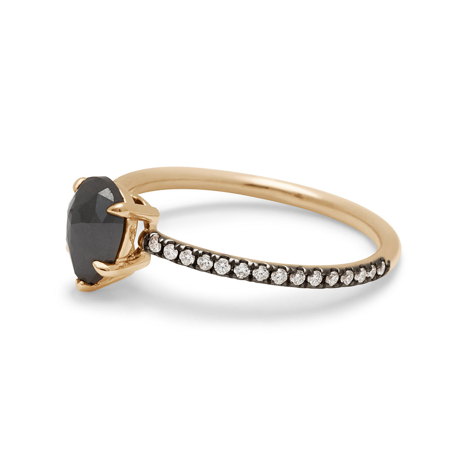 Angled view of a solitaire pear shaped black diamond ring with claw prongs with white diamond pave on the band set in black rhodium and yellow gold.