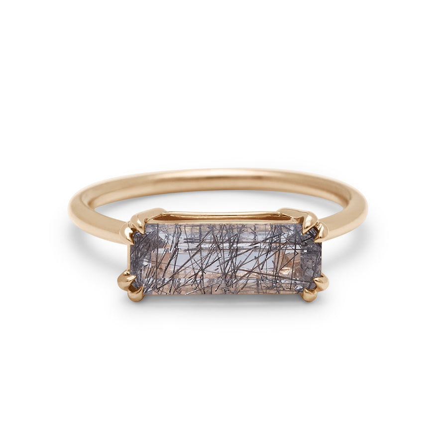 An elongated east/west solitaire ring with an elongated emerald shape black rutilated quartz stone set in yellow gold.