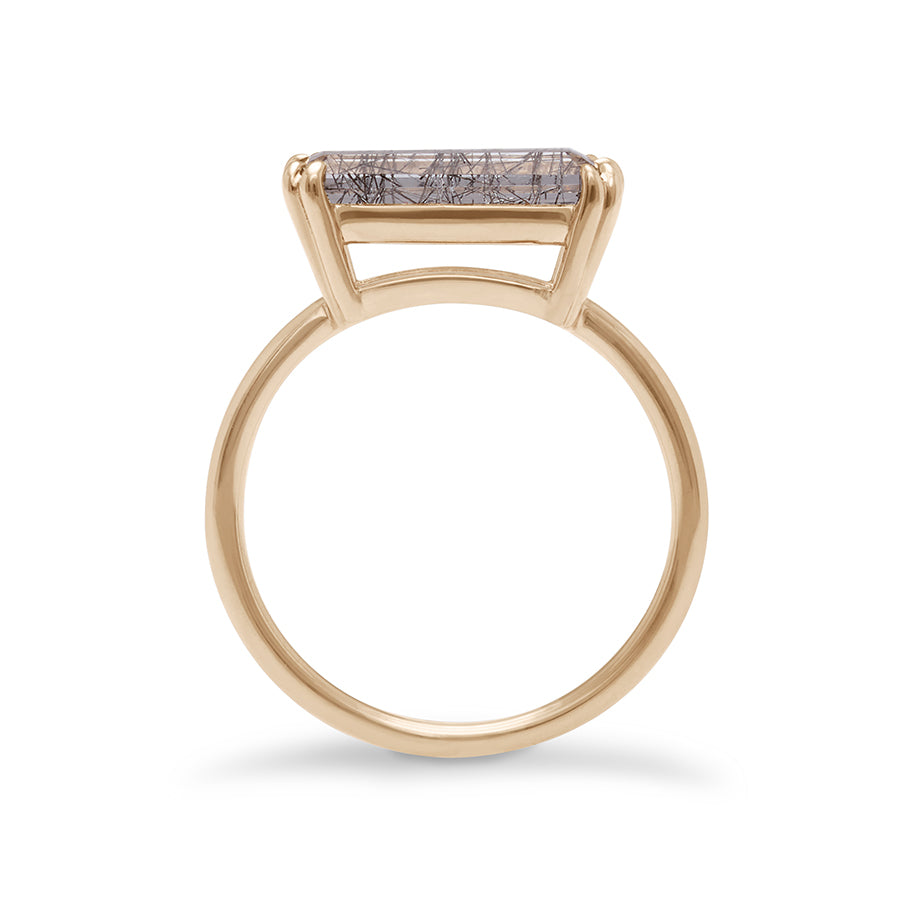 Side view of an elongated east/west solitaire ring with an elongated emerald shape black rutilated quartz stone set in yellow gold.