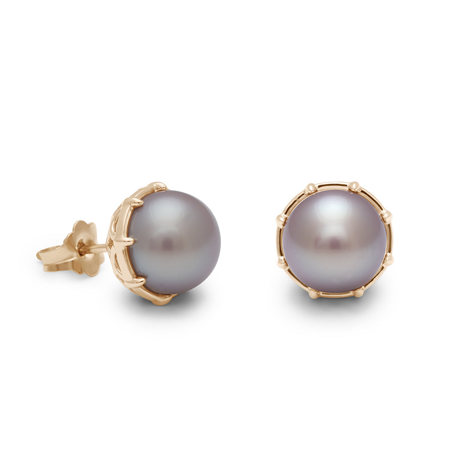 A pair of lilac pearl studs set in yellow gold one earring angled.