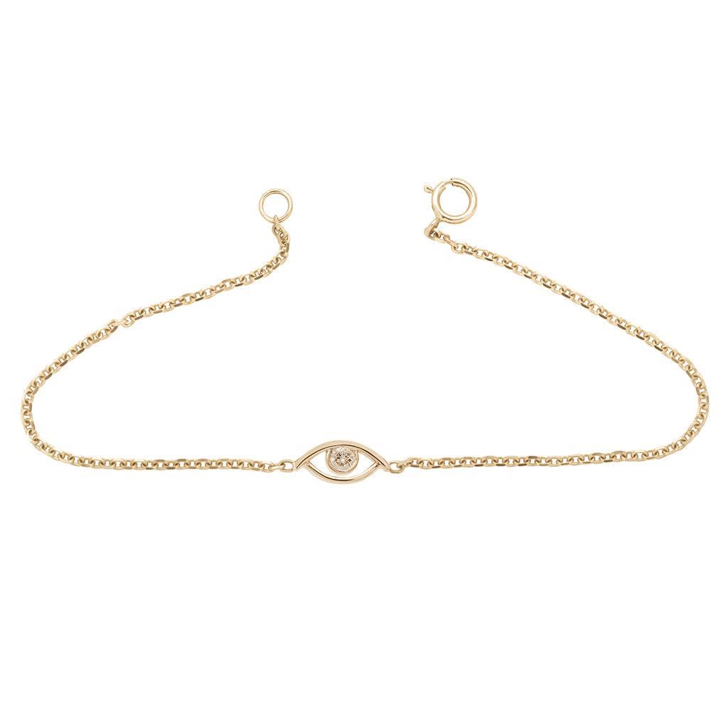 An evil eye charm with a champagne diamond center set in yellow gold on a yellow gold chain bracelet.