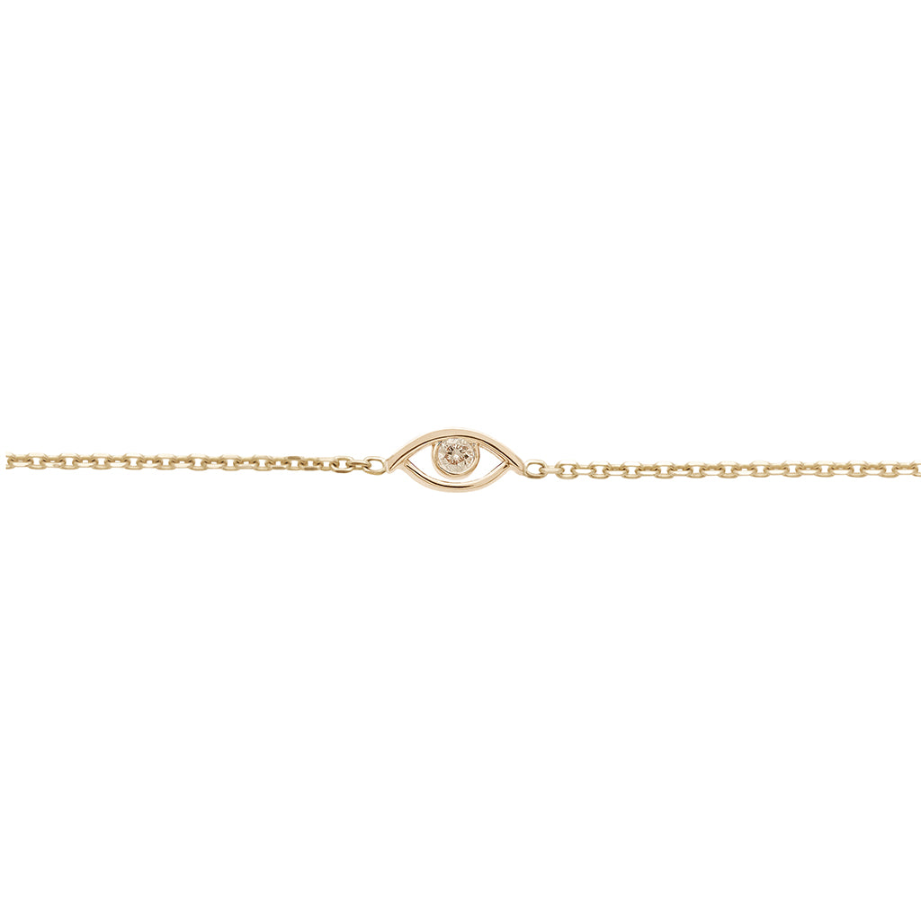 A zoomed in view of an evil eye charm with a champagne diamond center set in yellow gold on a yellow gold chain bracelet.