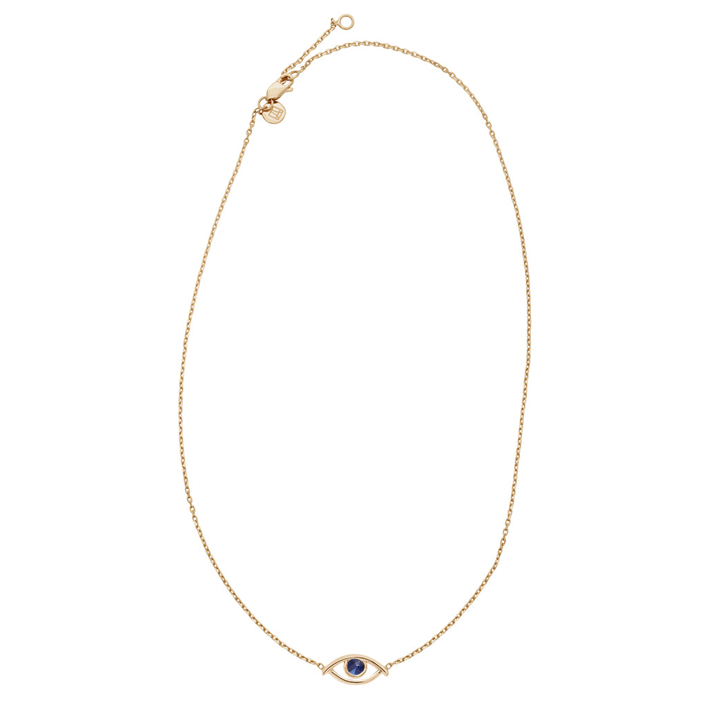 A zoomed out view of a choker with an evil eye charm with a blue sapphire stone in the center set on a yellow gold chain.