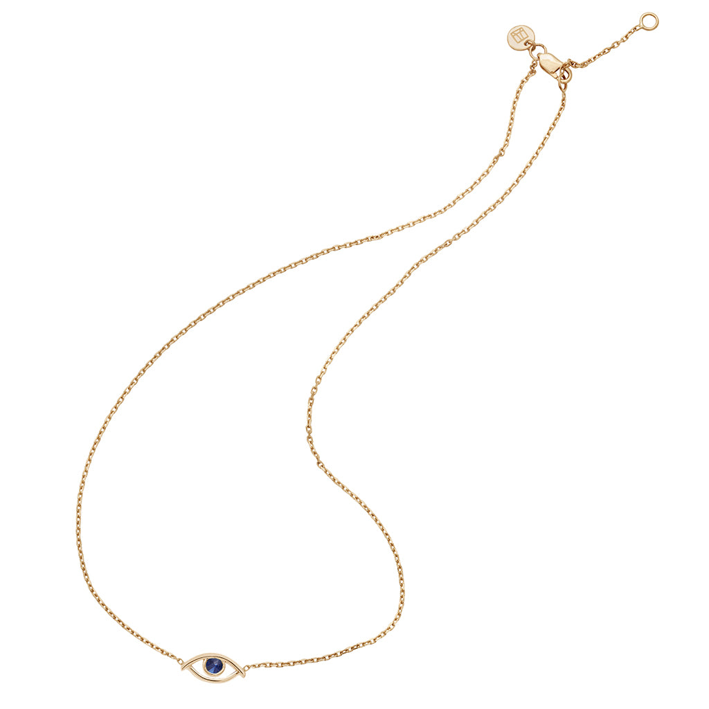 A zoomed out view of a choker with an evil eye charm with a blue sapphire stone in the center set on a yellow gold chain with a curved style.