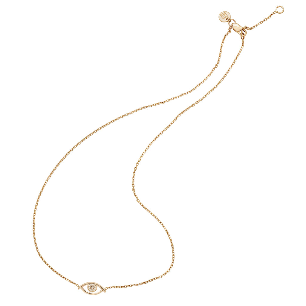 A zoomed out view of a choker with an evil eye charm with a champagne diamond in the center set on a yellow gold chain with a curved style.