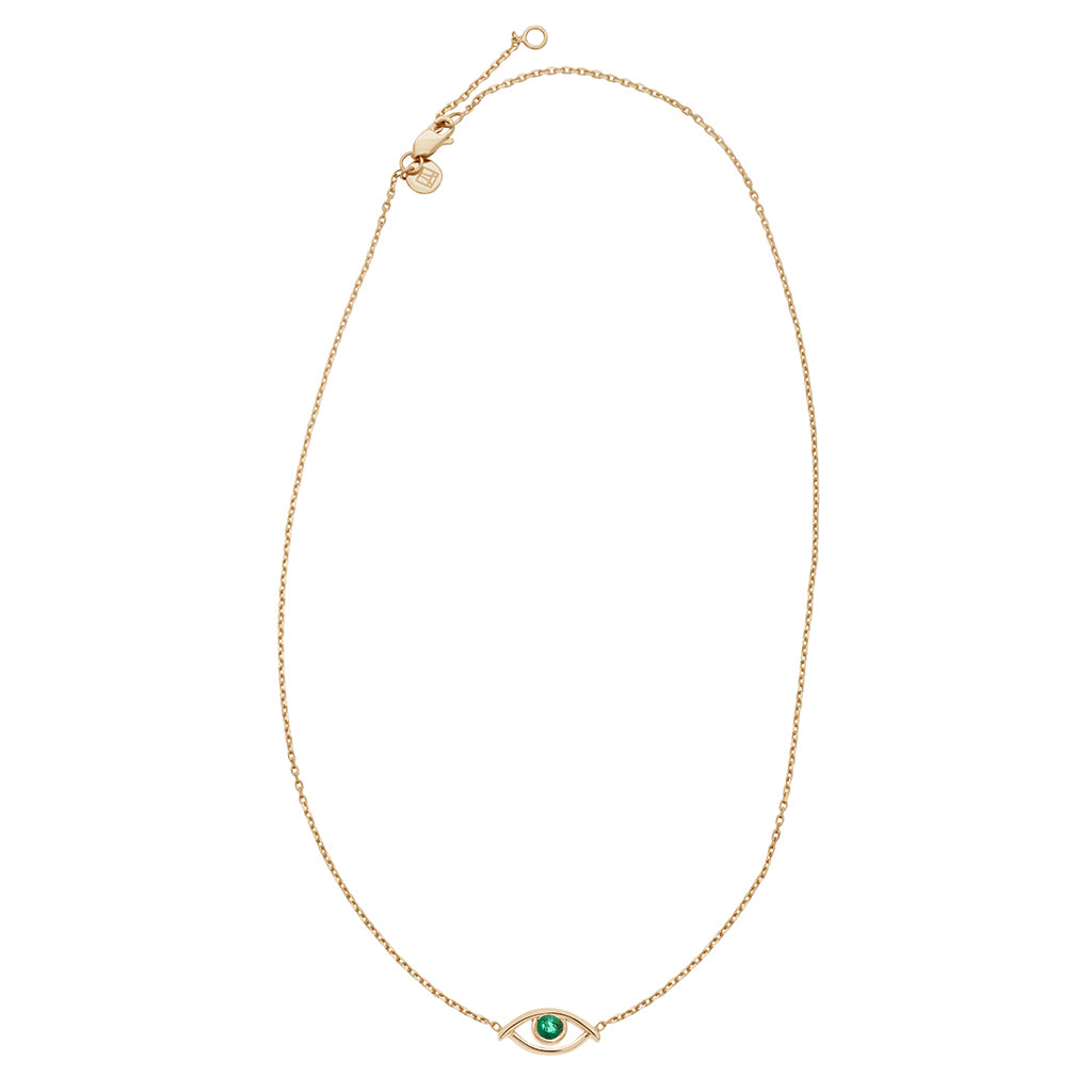 Zoomed out view of a choker with an evil eye charm with an emerald stone in the center set on a yellow gold chain.