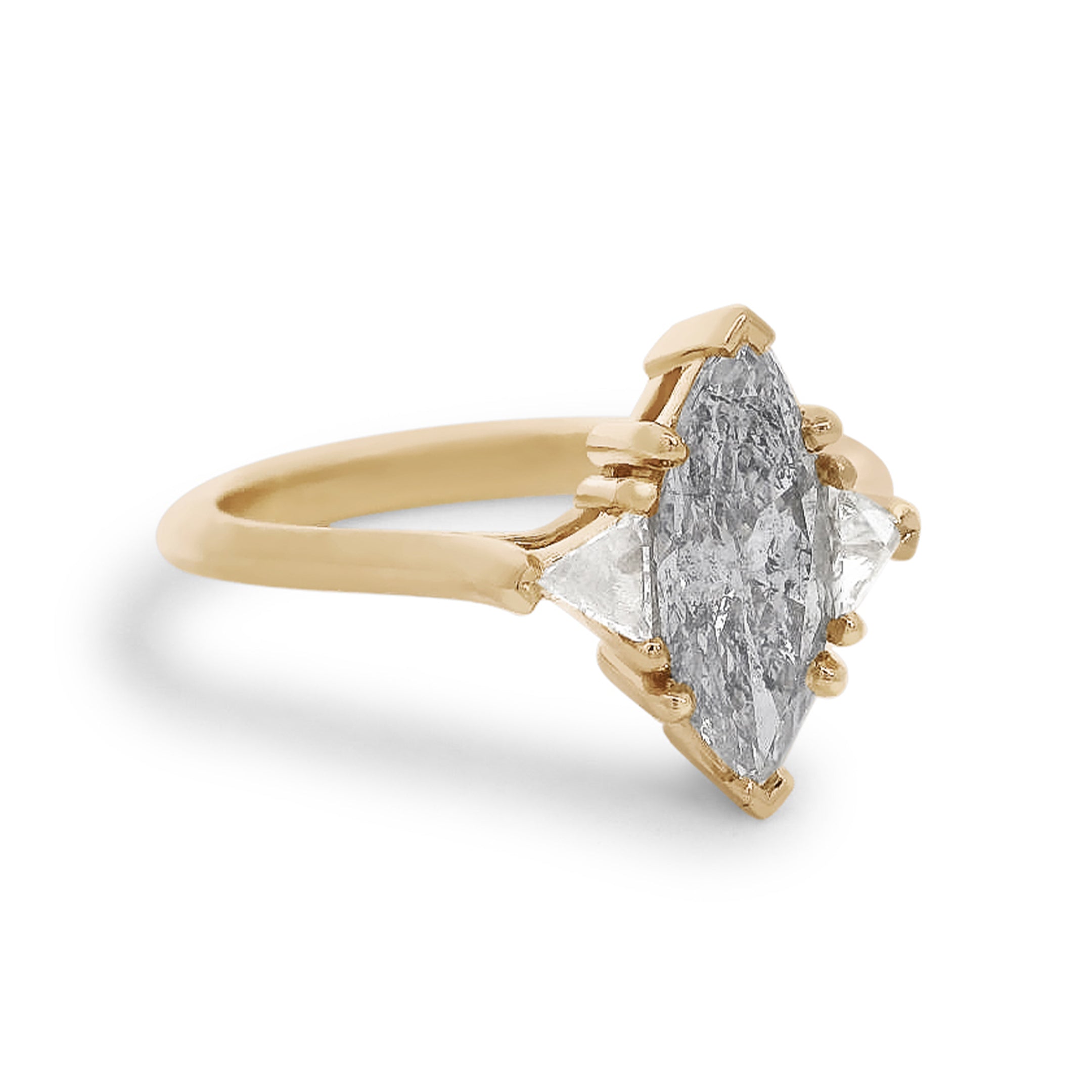Three stone ring featuring a marquise cut grey diamond with white trillion diamond side stones set in yellow gold. 